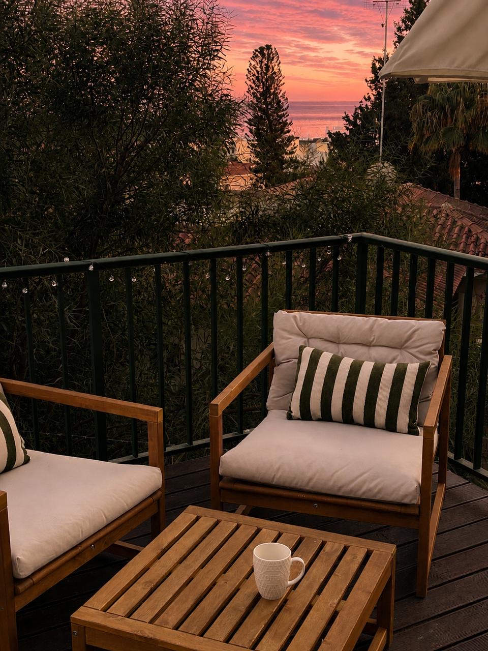 Sunset-view balcony with cozy seating and a peek of the ocean