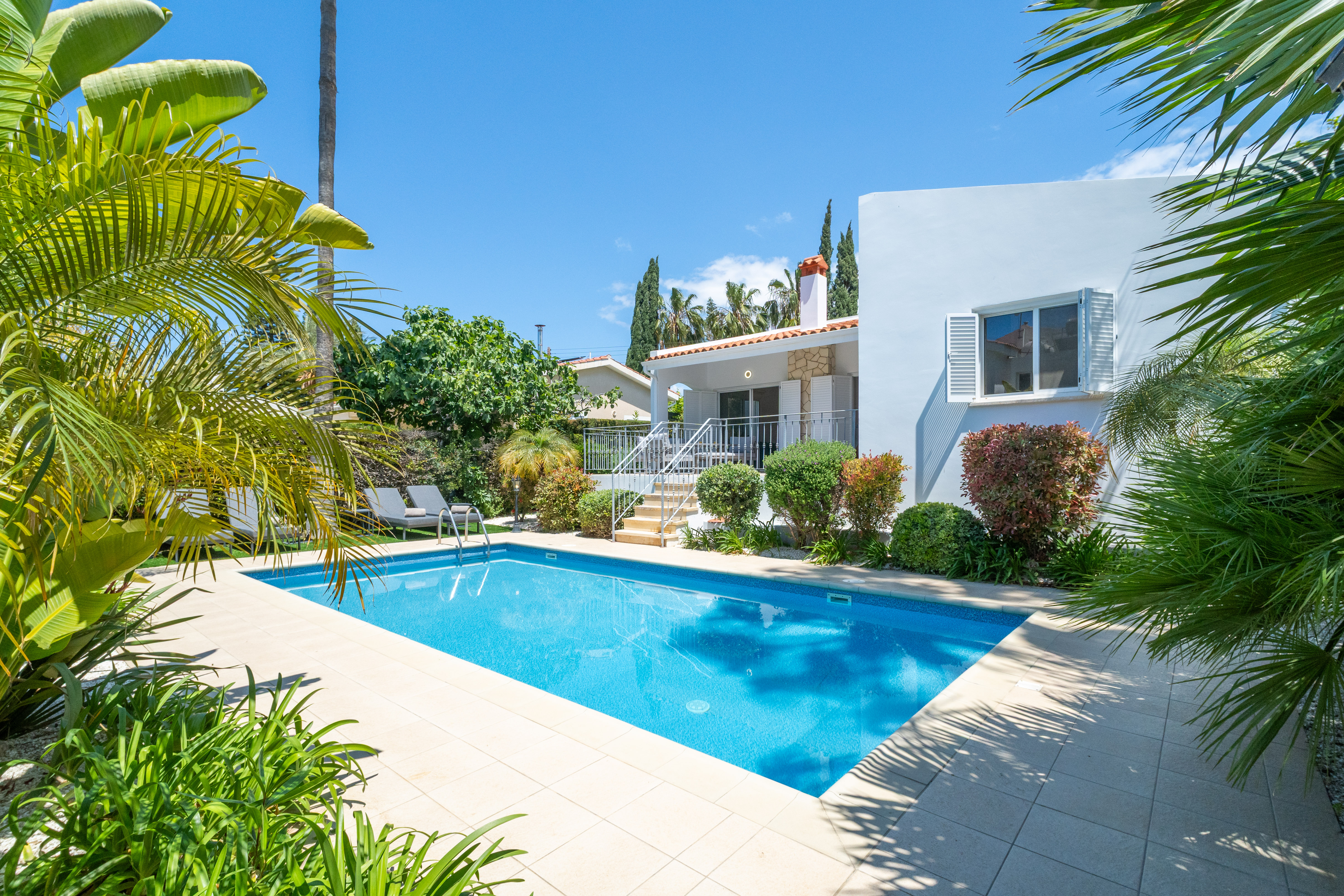 Mediterranean villa with private pool, loungers, and tropical garden