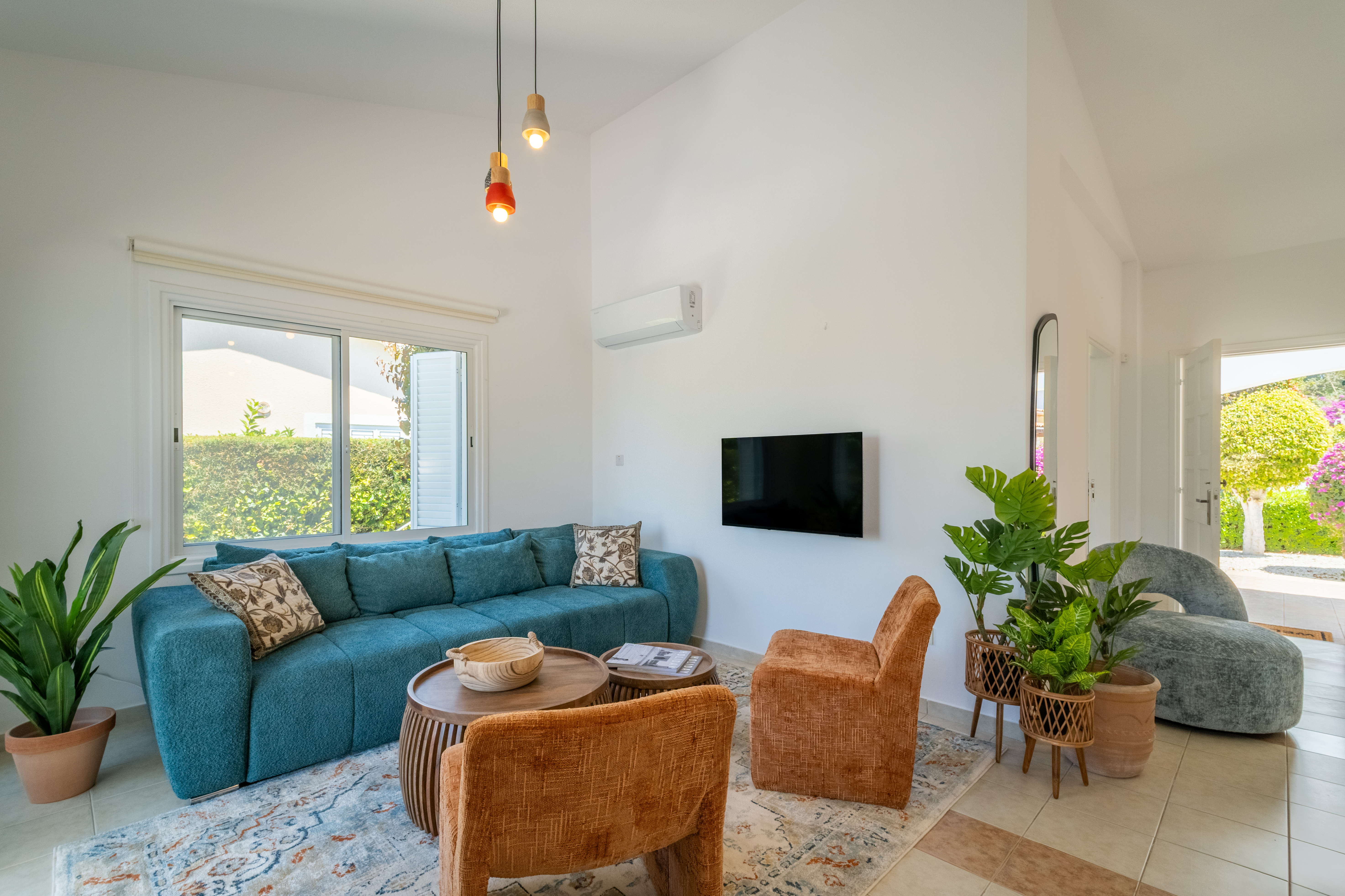 Sunny lounge with plush sofa, garden views, TV, and chic decor.