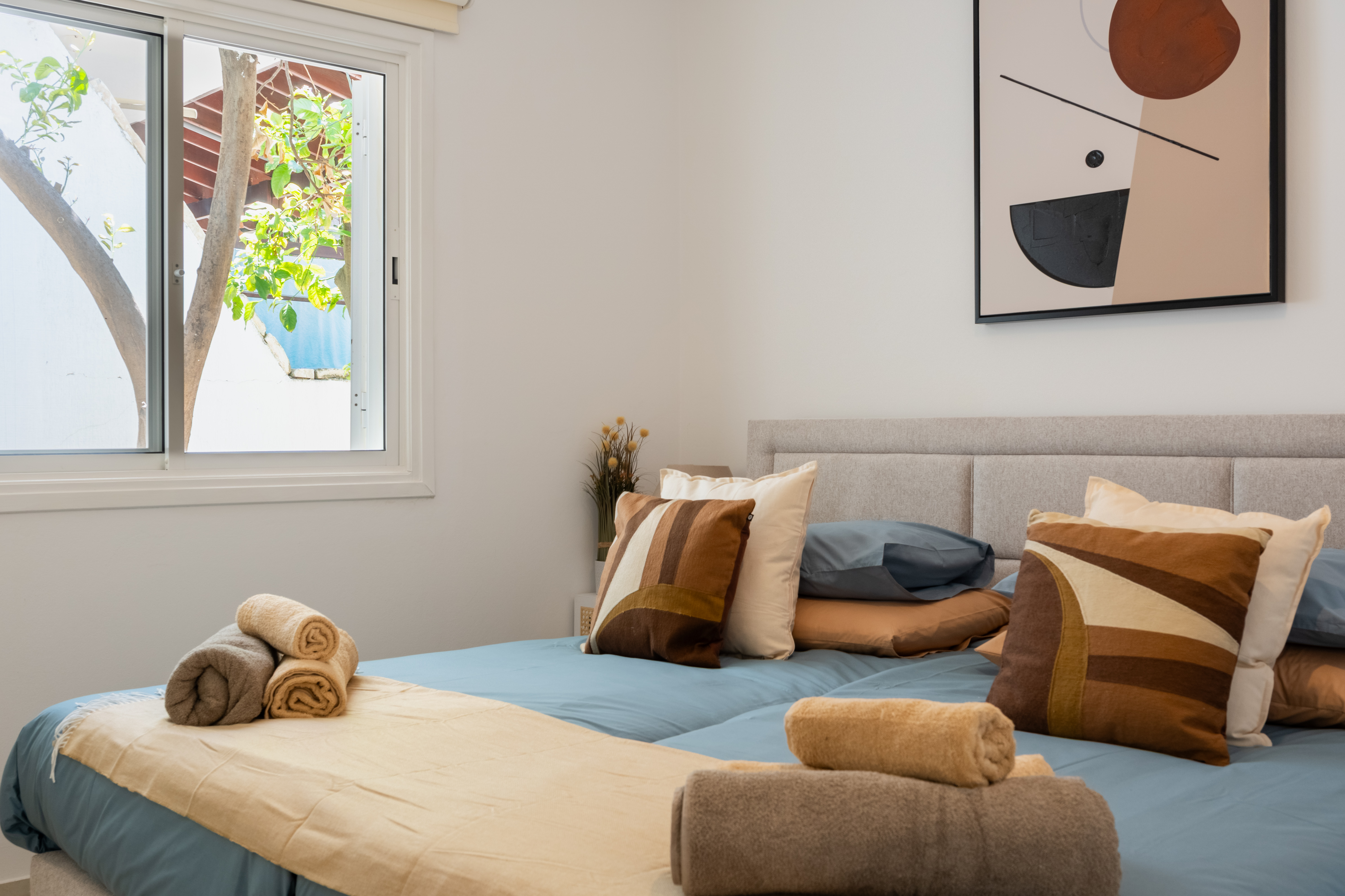 Sunny, modern bedroom with plush bedding and a garden-view window