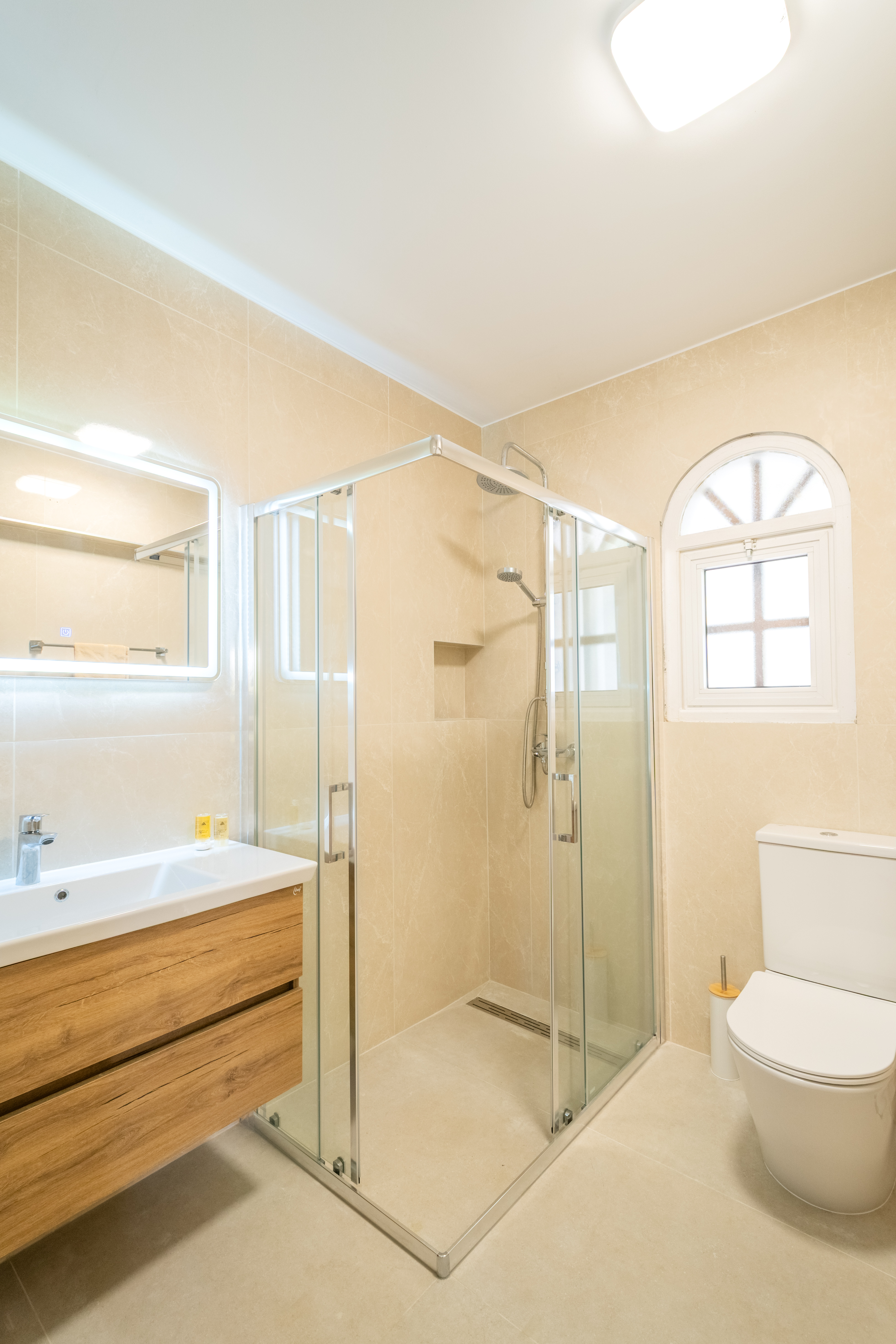 Bright spa-like bath with glass shower, lighted mirror, sleek vanity
