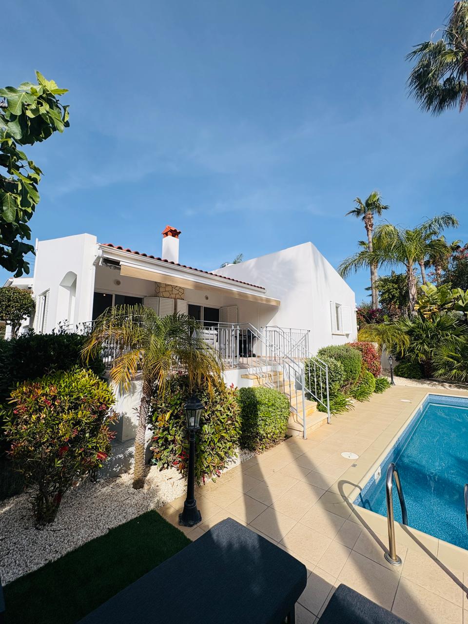 Sunny white villa with private pool, lush gardens, and a shaded terrace