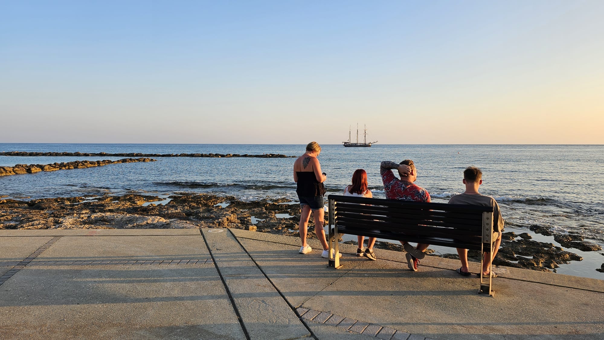 Seafront promenade with sunset views and sailboats, steps from shore