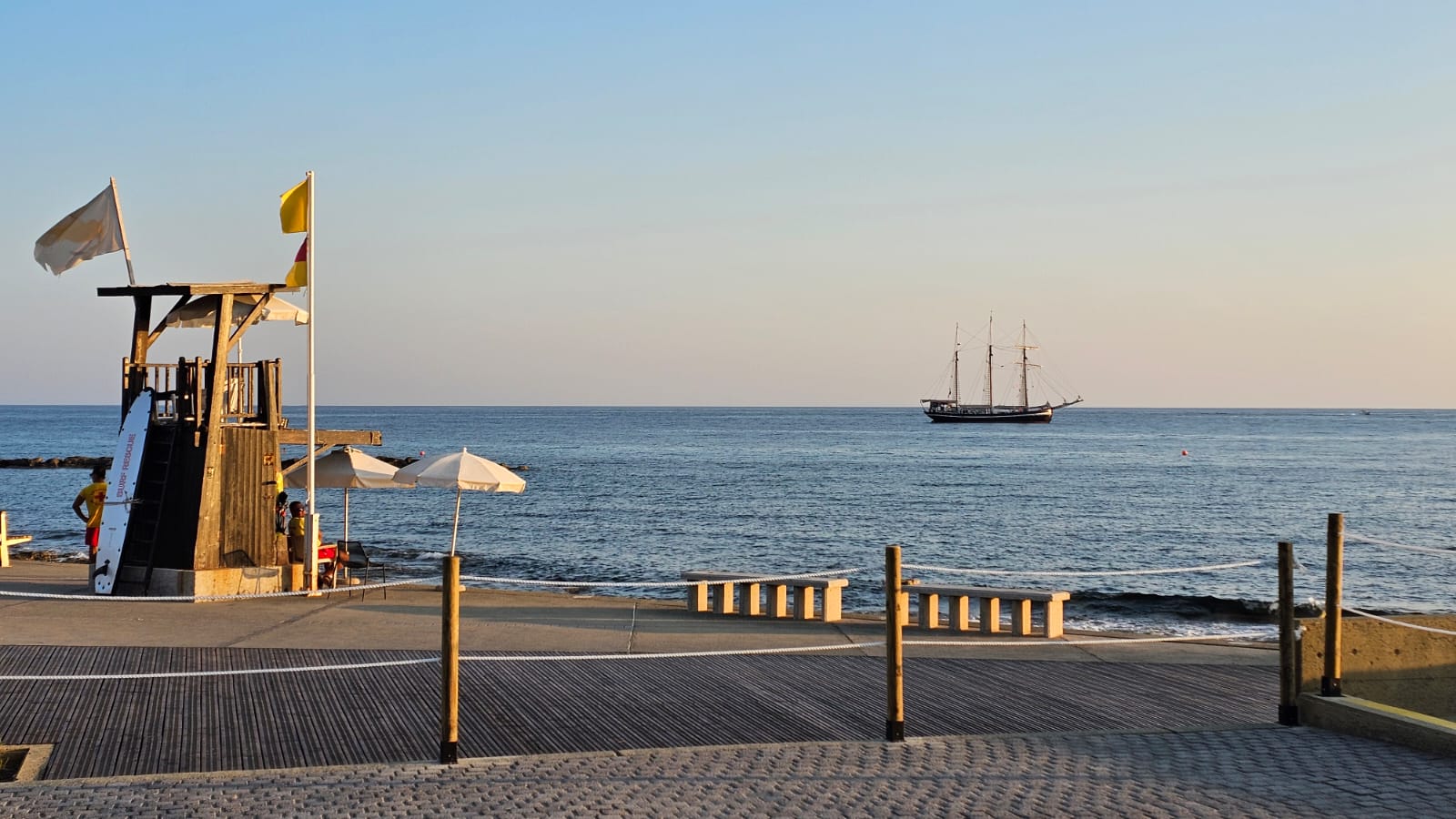 Oceanfront boardwalk with lifeguard tower and sunset ship views