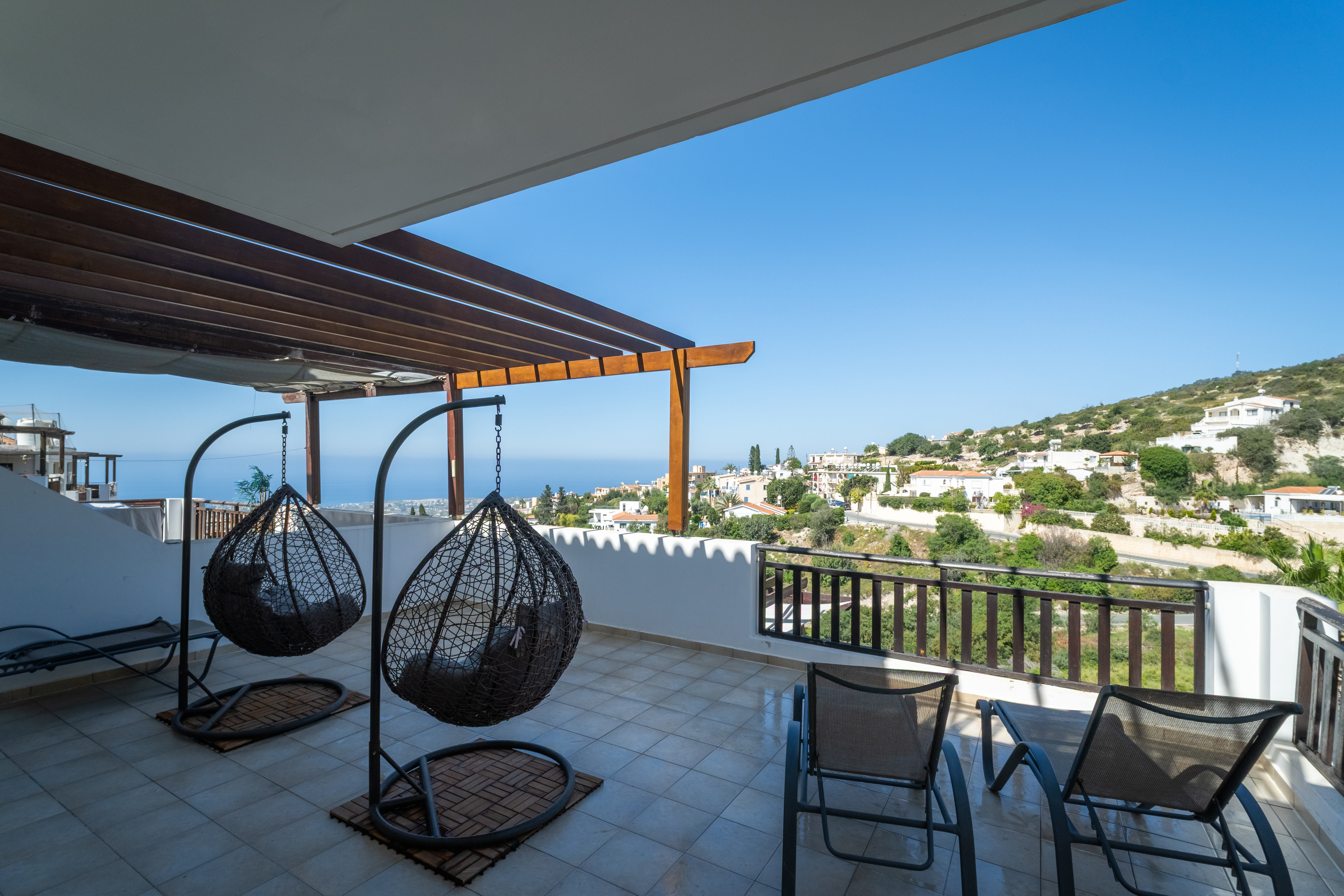 Sea-view terrace with egg chairs and loungers above a hillside village