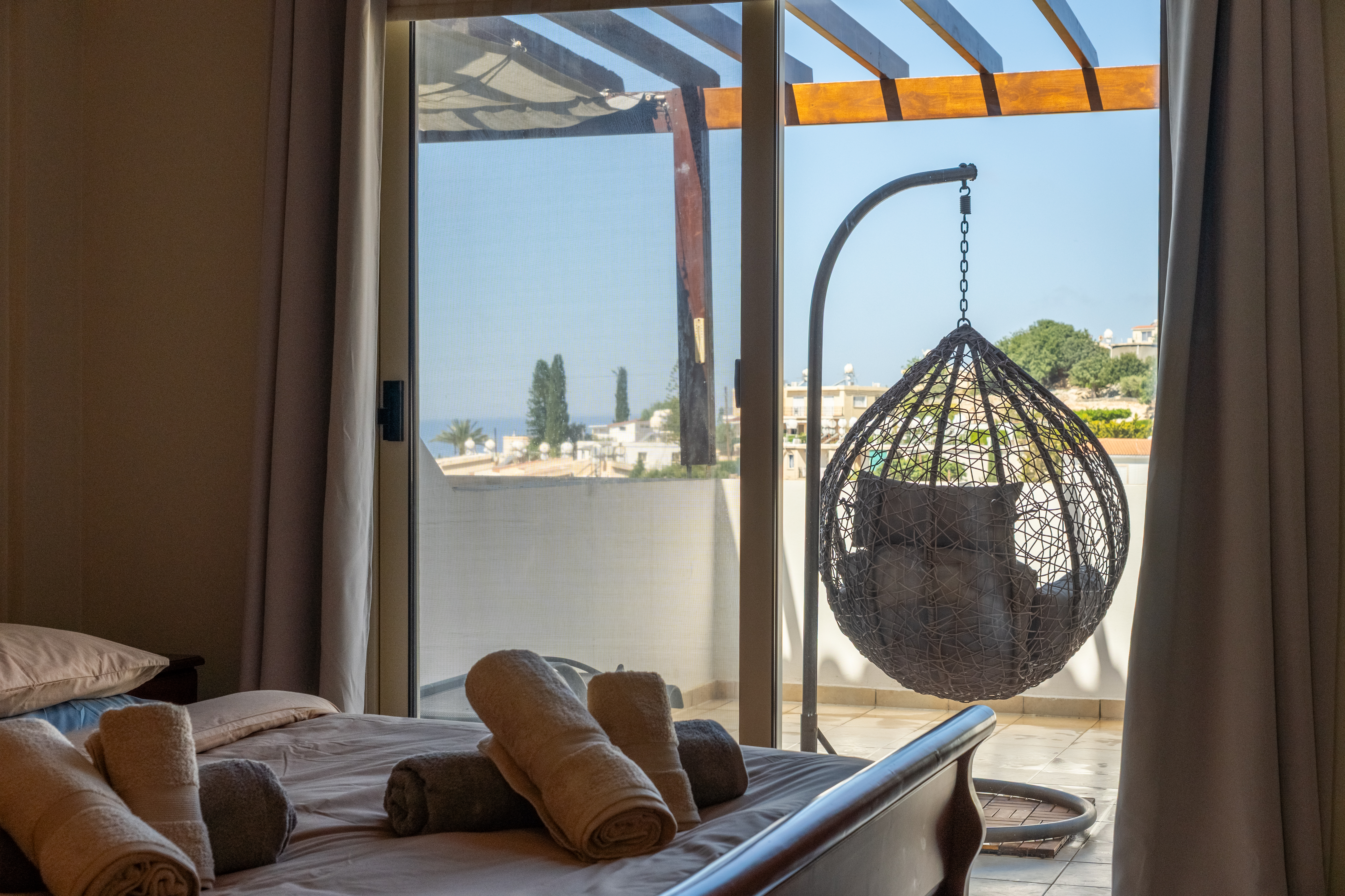 Sunny bedroom with balcony, egg chair & partial sea views, relax here.