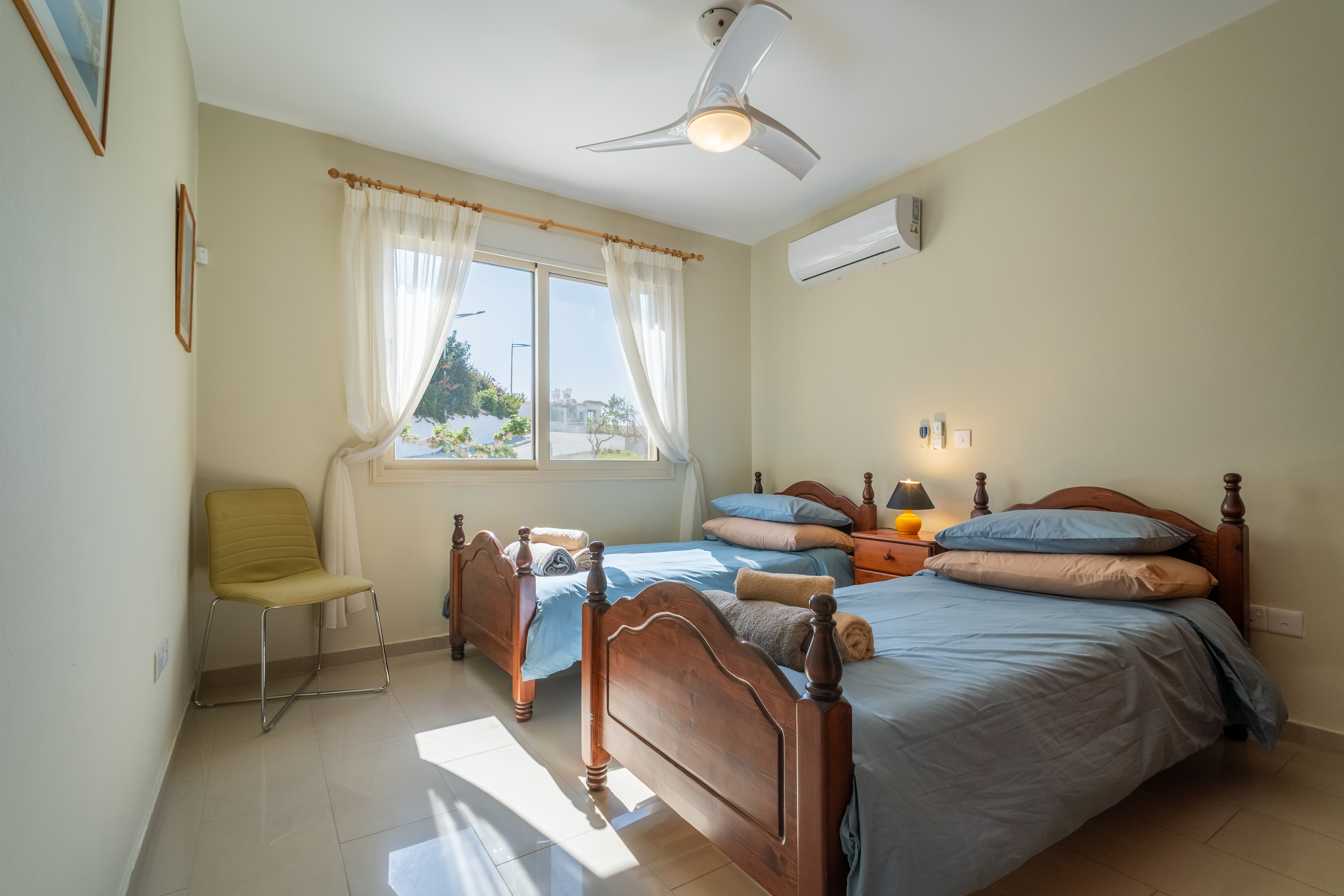 Sunny twin room with AC, ceiling fan, and fresh linens, ideal for friends.
