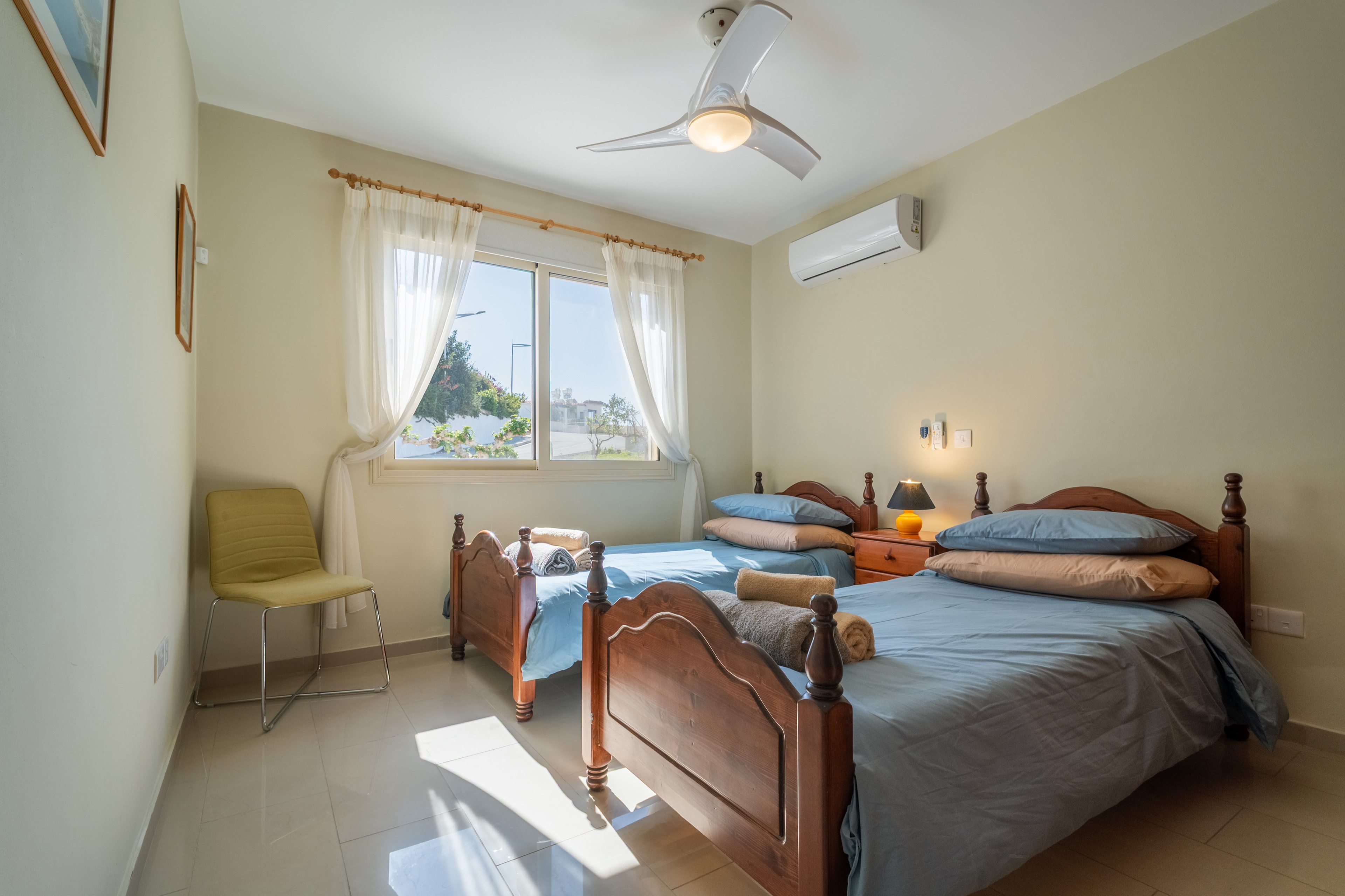 Sunny twin room with AC, ceiling fan, and fresh linens, ideal for friends.