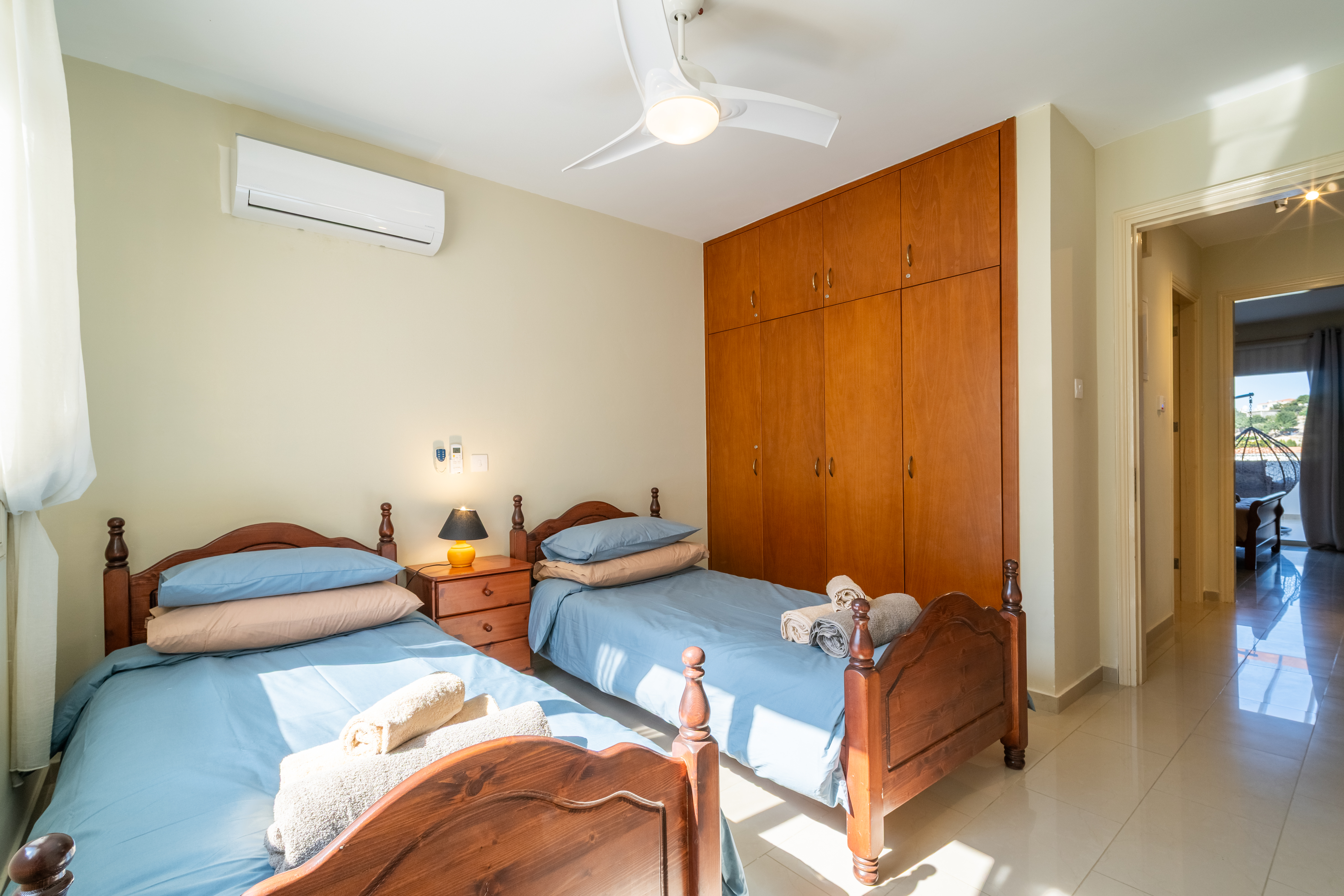 Sunny twin bedroom with AC, ceiling fan, and ample built-in storage