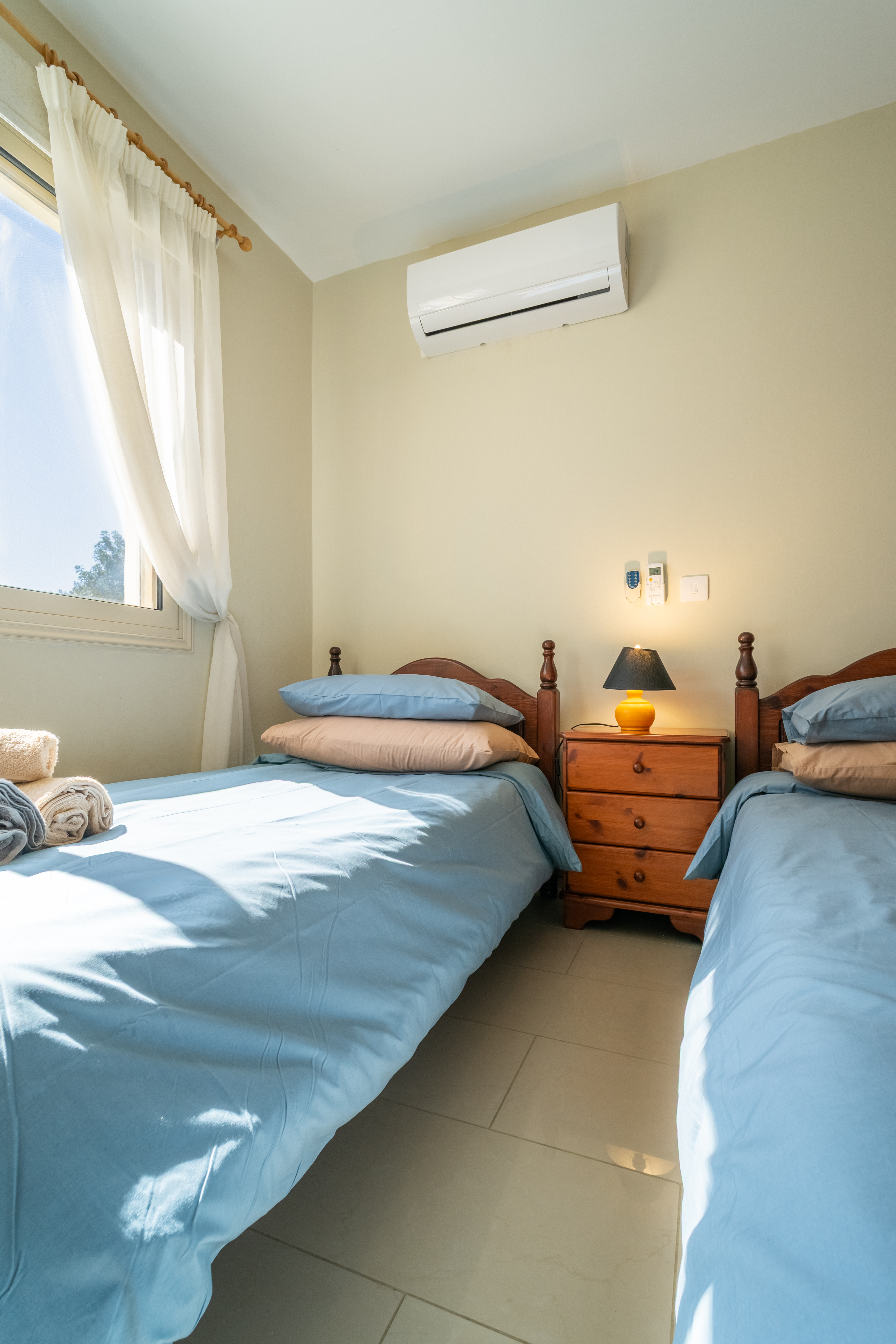 Sunny twin bedroom with AC, fresh linens and cozy bedside lamp
