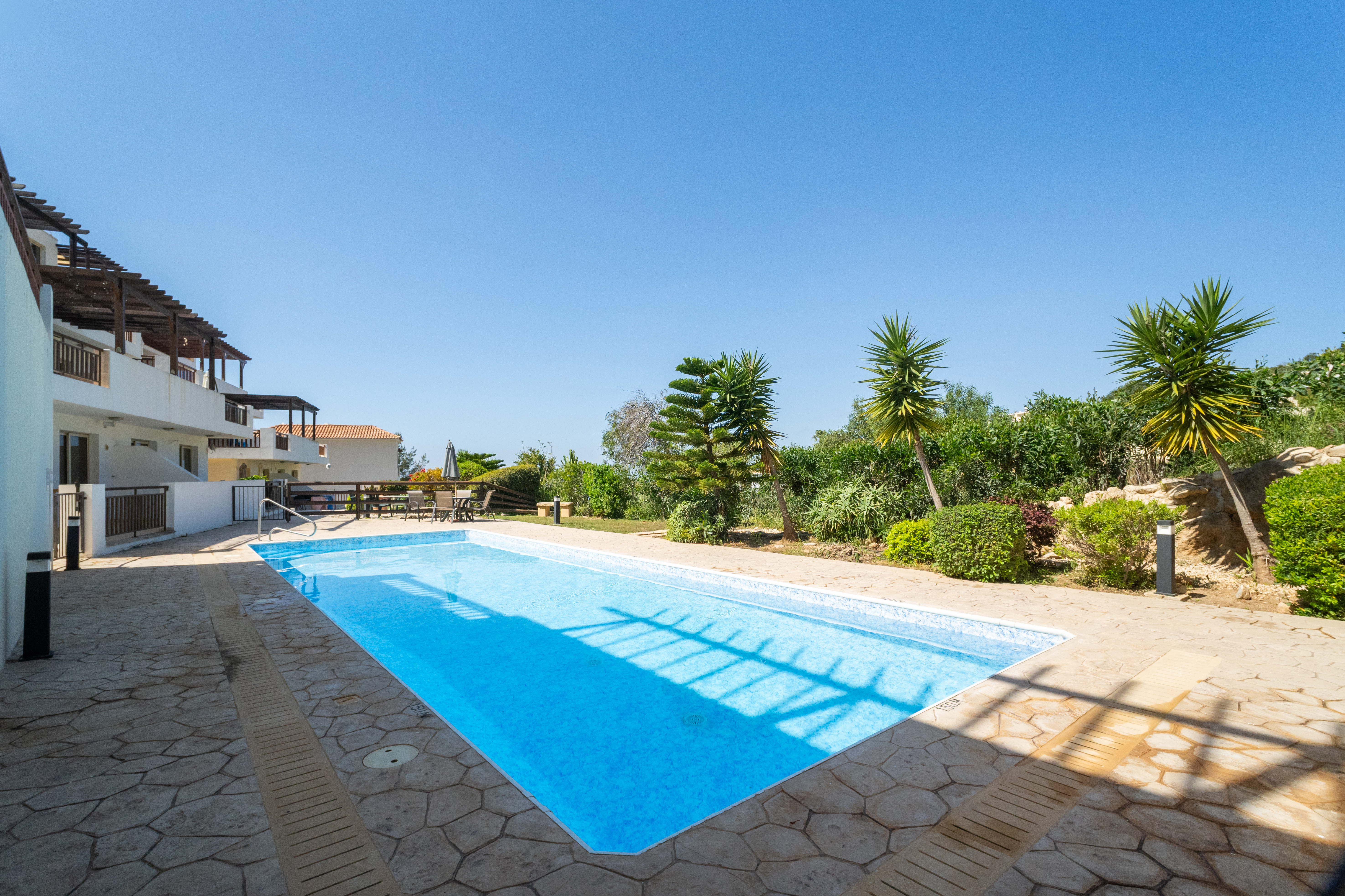 Sunny pool, stone patio, and lush gardens, perfect for lazy days.