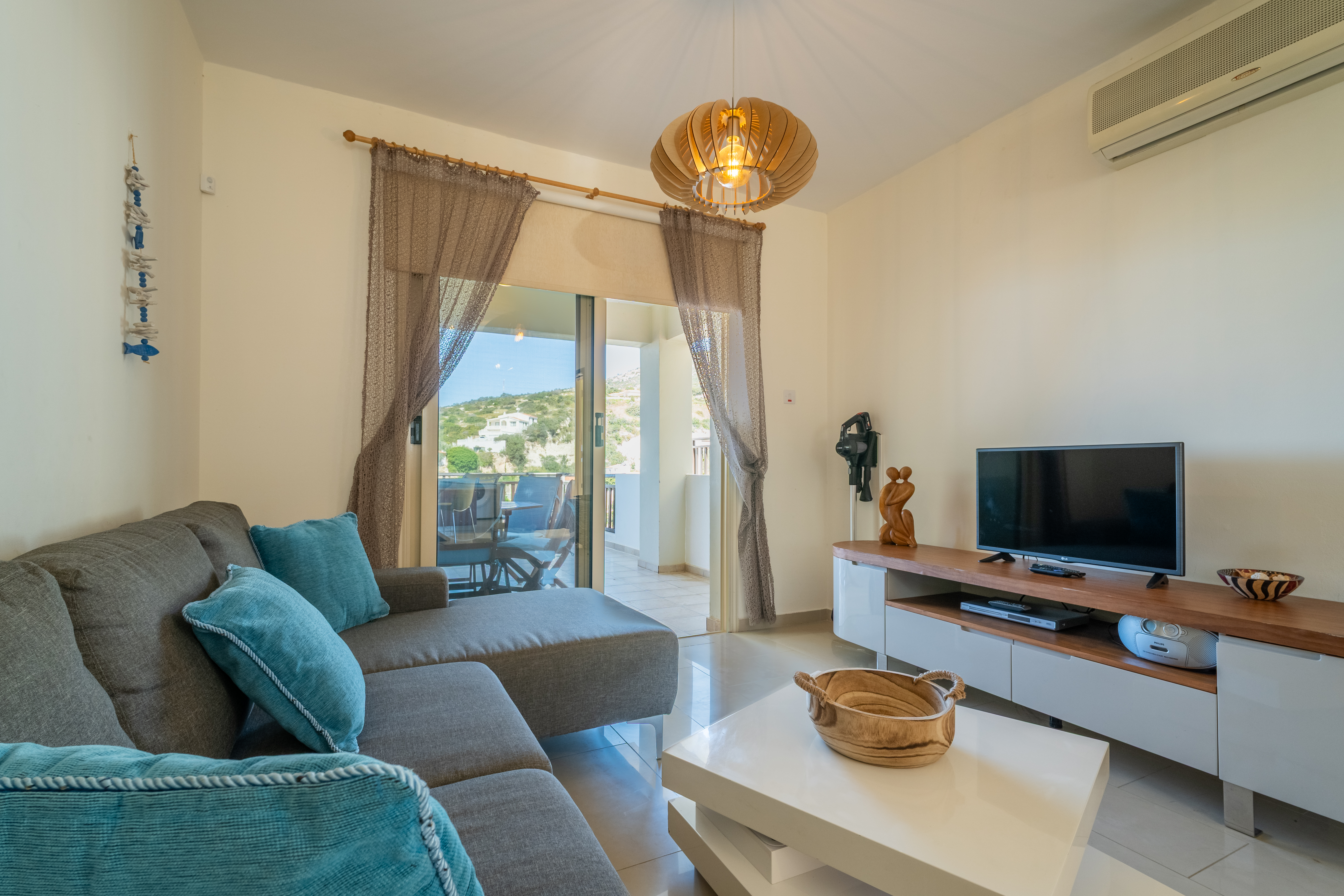 Bright lounge with balcony dining, hillside views, AC, and flat-screen TV