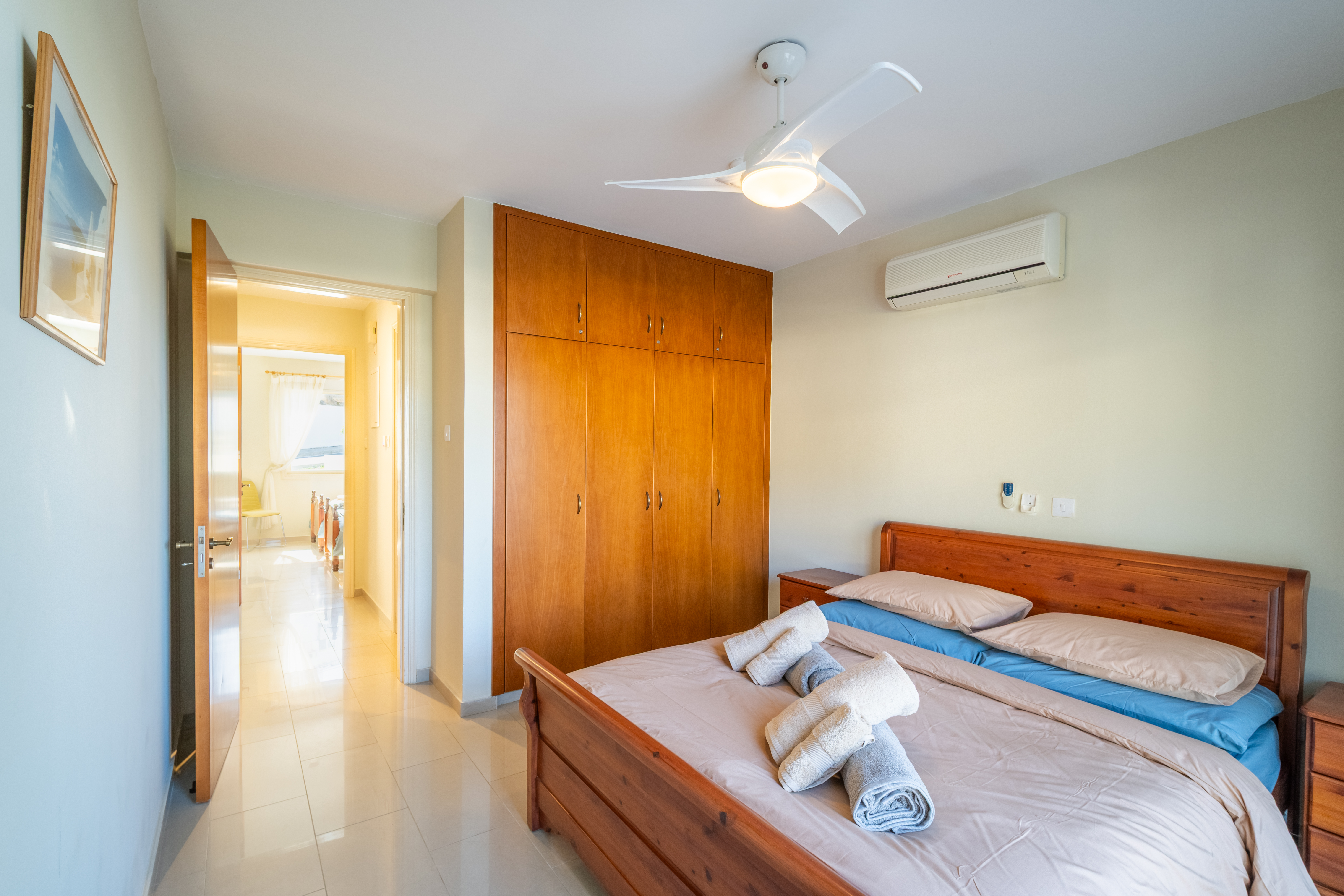 Sunny AC bedroom with ceiling fan, built-in wardrobe and cozy bed.